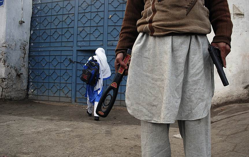Пешавар, Пакистан. Охранник с пистолетом и металлодетектором возле школы, где возобновились занятия. Работа пакистанских школ была приостановлена после теракта в военном училище Пешавара
