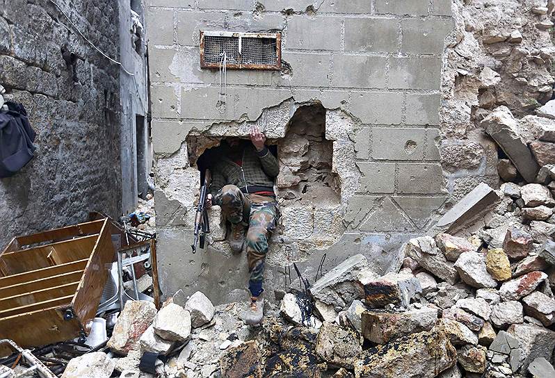 Алеппо, Сирия. Боец Свободной сирийской армии пробирается через дыру в стене дома