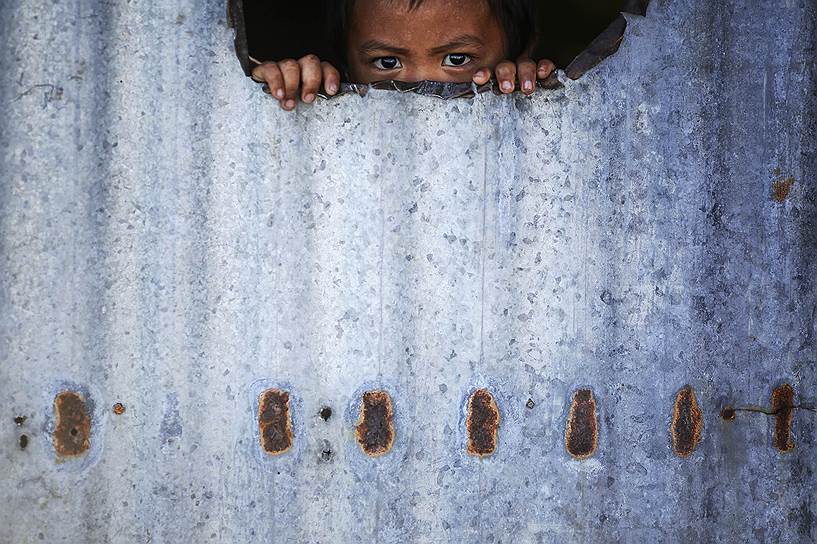 Таклобан, Филиппины. Ребенок выглядывает из-за стены импровизированного дома, в которых живут филиппинцы после тайфуна Хайян, который унес жизни 6300 человек