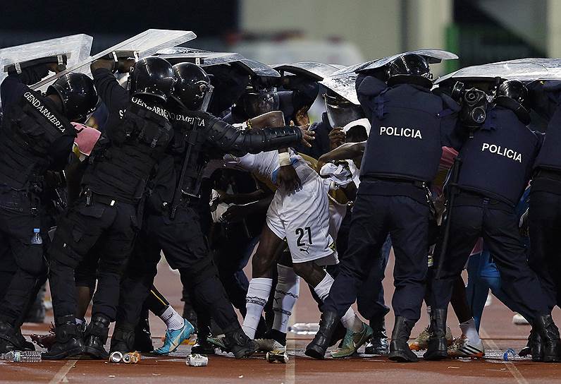 Малабо, Экваториальная Гвинея. Полицейские защищают футболиста сборной Ганы Джона Бойе от брошенных болельщиками Экваториальной Гвинеи предметов   