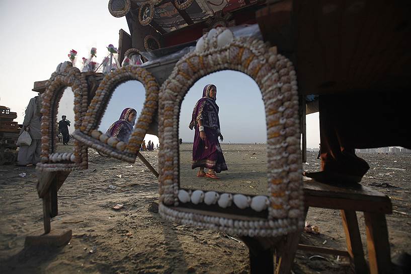 Карачи, Пакистан. Отражение женщины в зеркалах, украшенных ракушками и выставленных на продажу