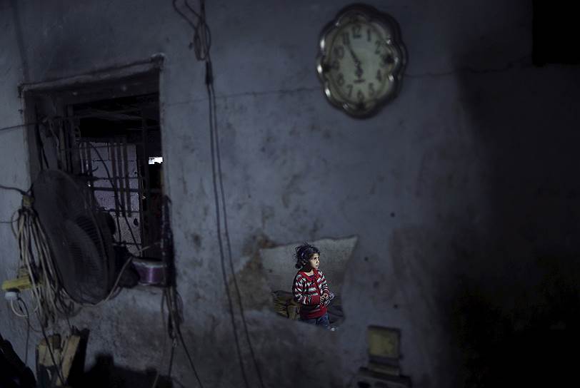 Газа, Палестина. Отражение девочки в доме, освещаемом свечой, во время перерыва в подаче электроэнергии