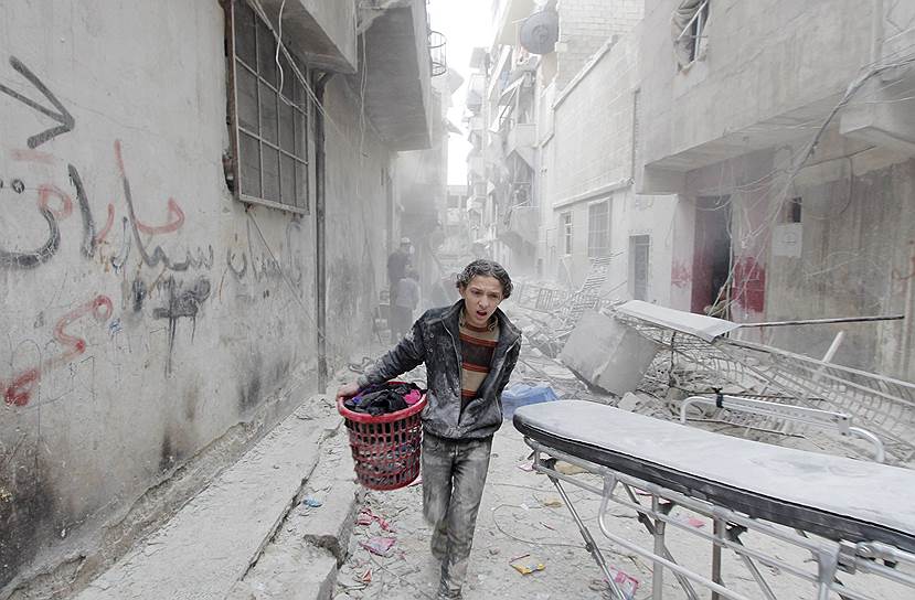Алеппо, Сирия. Мальчик выносит вещи из разрушенного дома, в который попала бомба