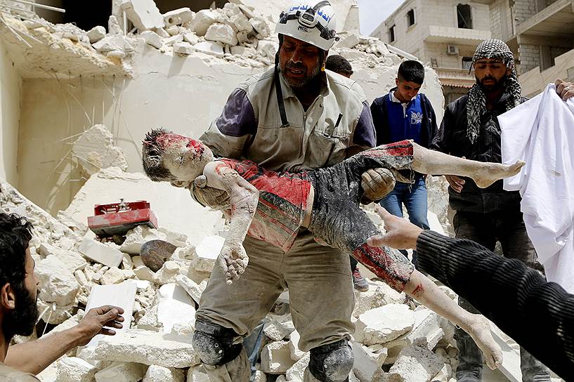 Автор: Катан Осам. Солдат войск Гражданской обороны несет тело ребенка, погибшего при налете авиации правительства(Сирия) 