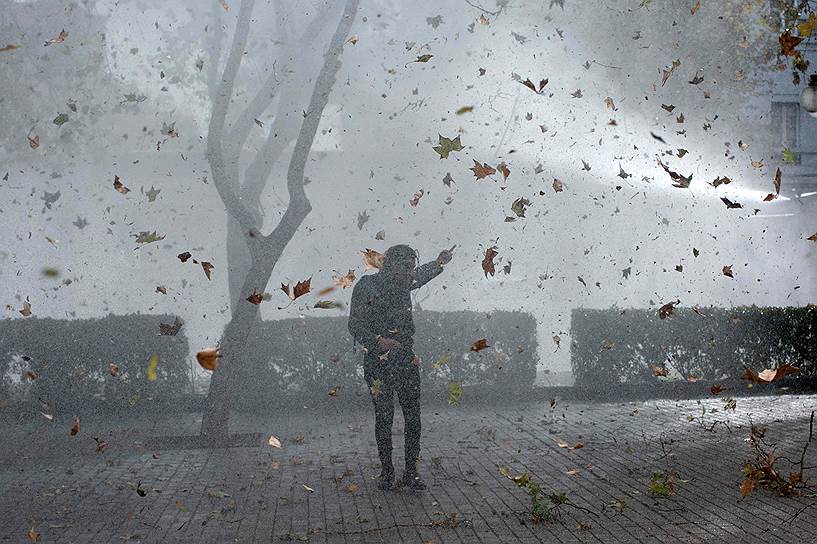 Сантьяго, Чили. Студент прикрывается рукой от брызгов из полицейских водометов во время демонстрации, устроенной с требованием реформирования системы образования