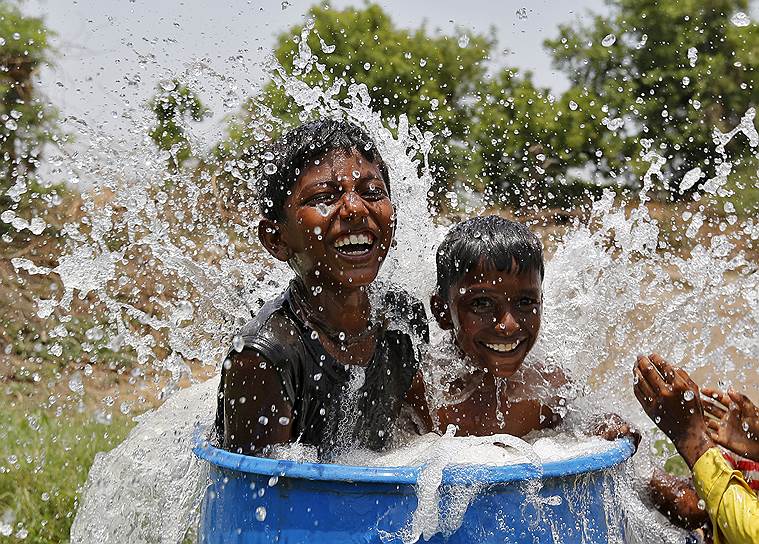 Ахмадабад, Индия. Дети спасаются от аномальной жары, сидя в ведре с водой