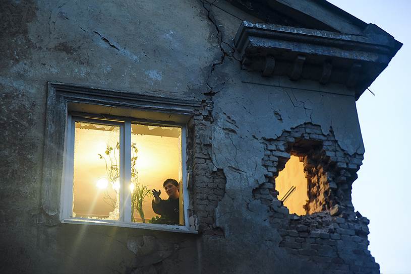 Донецк, Украина. Местный житель рассматривает повреждения города из окна своего полуразрушенного дома после артобстрела