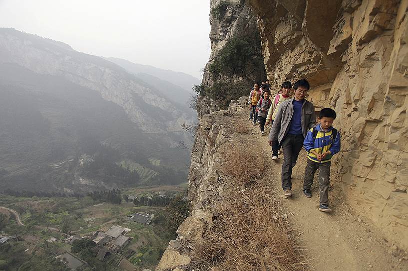 Ученики школы округа Бицзе (провинция Гуйчжоу КНР) ходят на занятия в сопровождении учителя, так как путь к школе лежит через горные опасные тропы