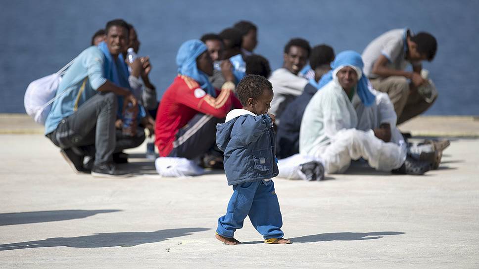 Аугуста, Италия. Ребенок гуляет возле мигрантов, которые отдыхают в порту после высадки с судна
