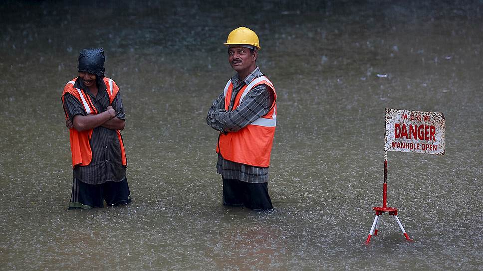 Мумбаи, Индия. Рабочие стоят на затопленной из-за проливных дождей дороге