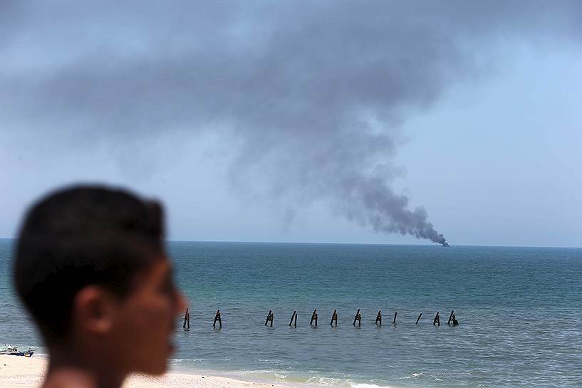 Рафах, Сектор Газа. Палестинец с берега смотрит на дым, поднимающийся от горящего египетского судна береговой охраны