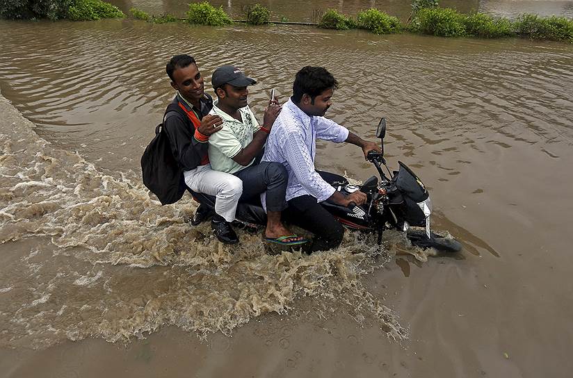 Ахмедабад, Индия. Местные жители на мотоцикле во время наводнения