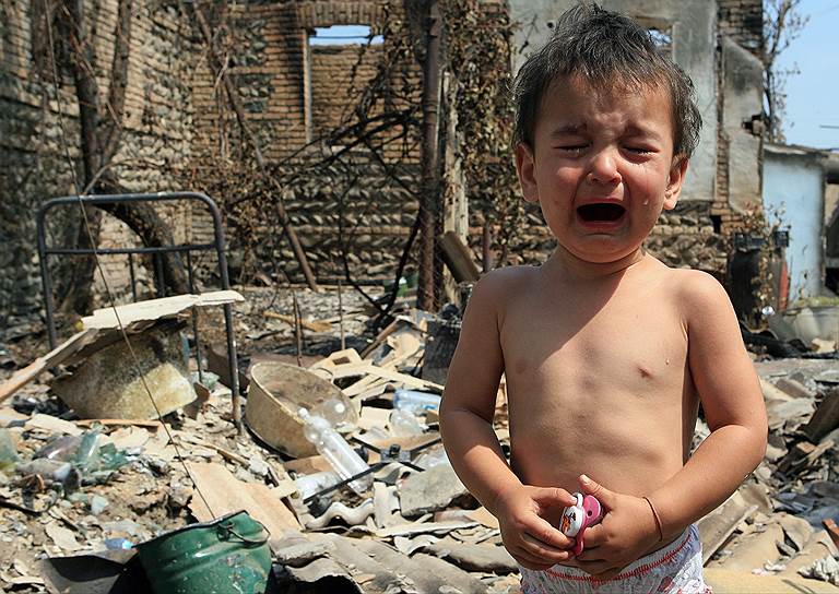Плачущий ребенок у разрушенного дома в Цхинвале