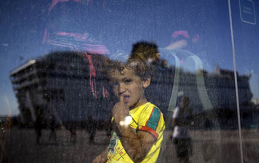 Афины, Греция. Ребенок-мигрант смотрит на прибыте пассажирского корабля в порт