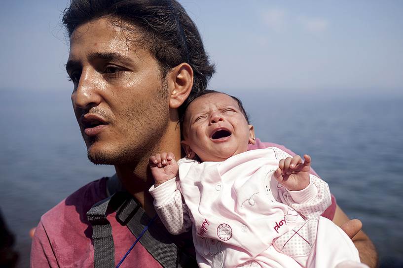 Лесбос, Греция. Сирийский беженец из Алеппо держит на руках месячную дочку после прибытия на греческий остров Лесбос
