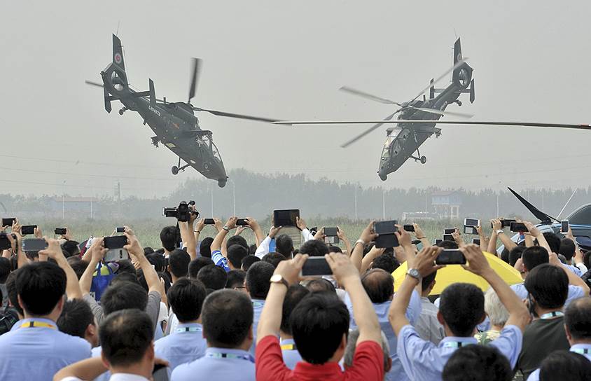 Тяньцзинь, Китай. Зрители во время показательного выступления боевых вертолетов Z-19 на выставке China Helicopter Exposition