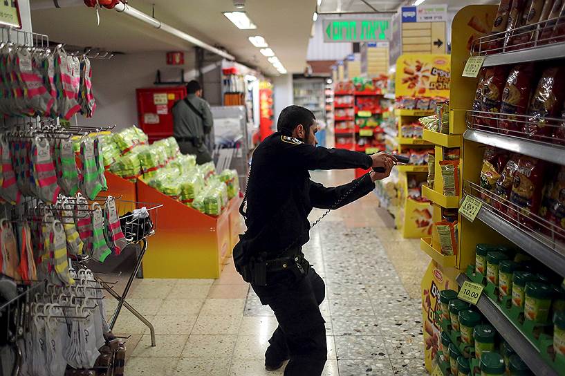 Иерусалим, Израиль. Сотрудник полиции обыскивает супермаркет в поисках палестинца, ударившего ножом 70-летнюю женщину