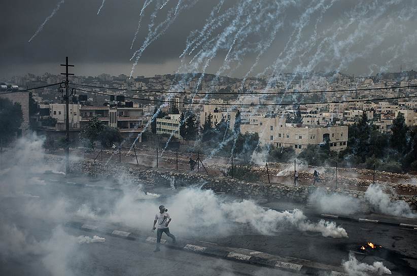 Вифлеем, Палестина. Демонстрант, убегающий от гранат со слезоточивым газом, выпущенных израильскими военными во время столкновений