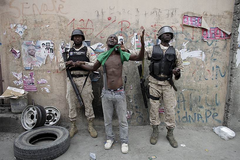 Порт-о-Пренс, Гаити. Демонстрант с двумя мачете, задержанный полицией во время акции протеста против результатов президентских выборов