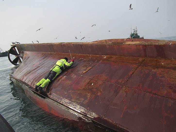 Желтое море, Южная Корея. Спасатель южнокорейской береговой охраны работает на потерпевшем крушение рыболовном судне