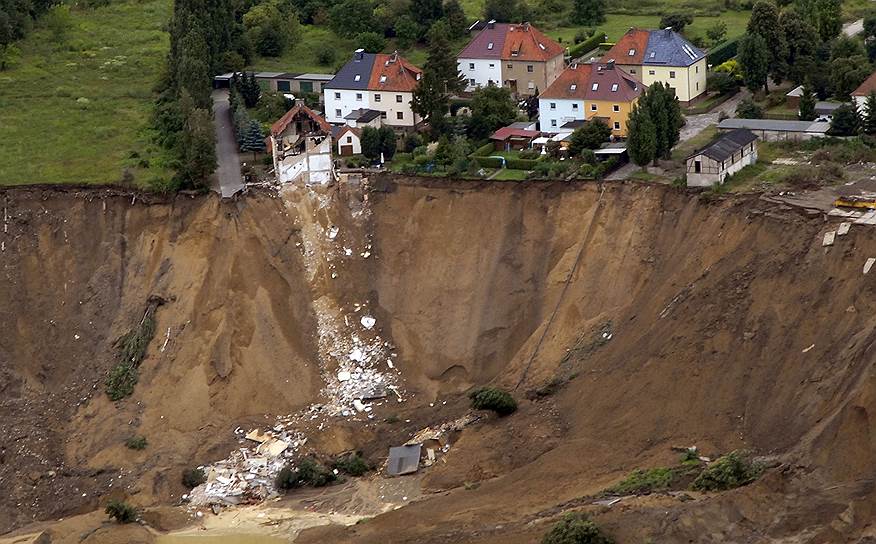 2009 год, Германия. Вид с воздуха на разрушенную дорогу и обломки жилого дома в деревне Нахтерштедт. Почти 2,8 млн куб. м. берега обвалились в искусственное озеро Конкордиа на месте затопленного карьера, где ранее велась добыча угля