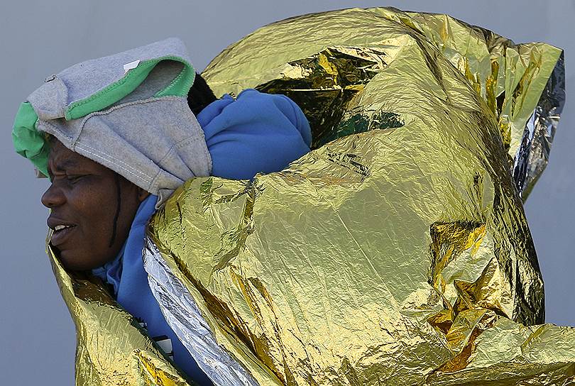 Аугуста, Италия. Беженка, обернутая в термоодеяло, во время выгрузки группы спасенных мигрантов с борта военного корабля «Cigala» в сицилийском порту