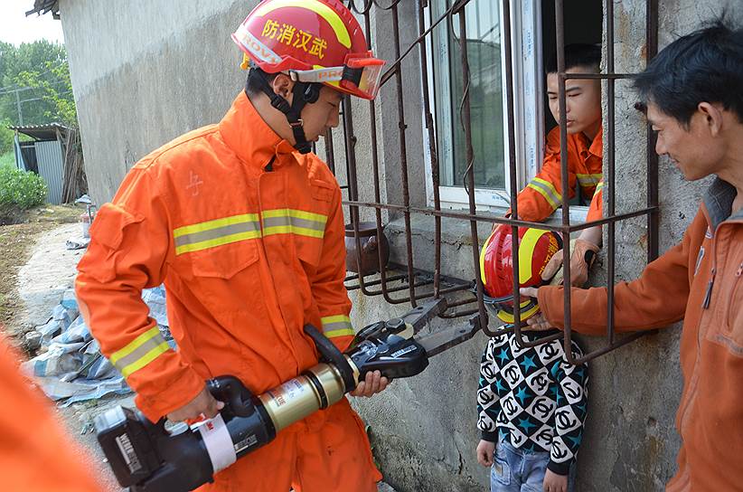 Ухань, Китай. Спасатели вытаскивают мальчика, застрявшего в оконной решетке своего дома