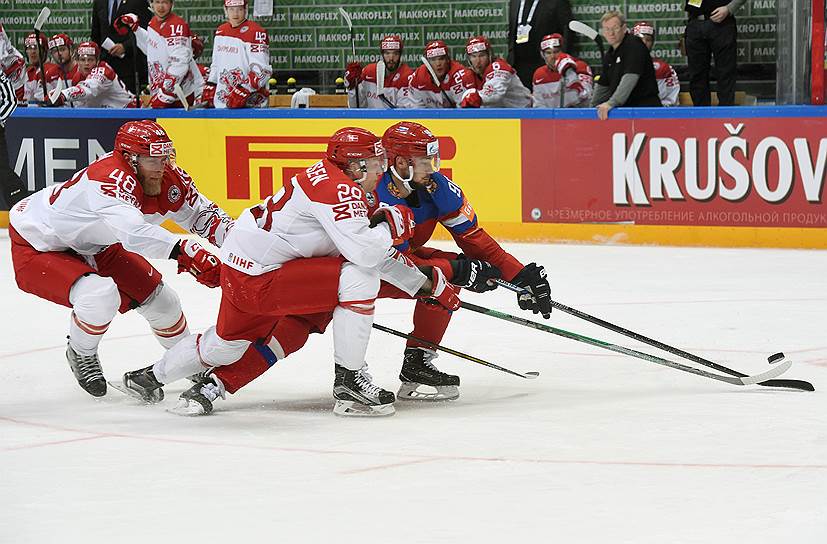 Игрок сборной России Александр Бурмистров (справа) в борьбе за шайбу с защитниками Дании