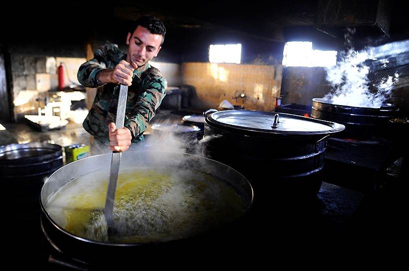 Дамаск, Сирия. Рекрут сирийской армии готовит еду в тренировочном лагере