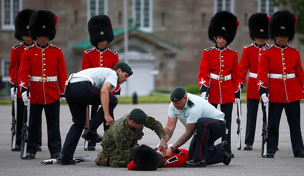 Квебек, Канада. Военные помогают члену почетного караула, упавшему в обморок в ожидании визита президента Мексики