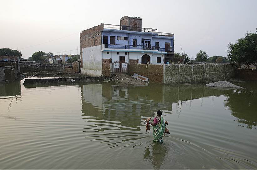 Аллахабад, Индия. Женщина возвращается в дом после наводнения 