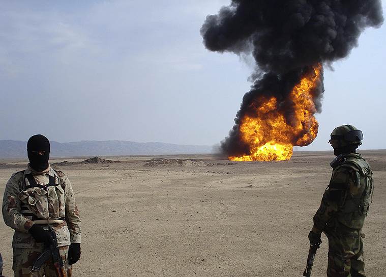 Иракские солдаты смотрят, как горит нефтепровод в Киркуке