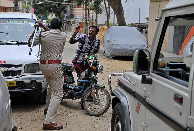 Бангалор, Индия. Полицейский замахивается на местного жителя, который нарушил комендантский час