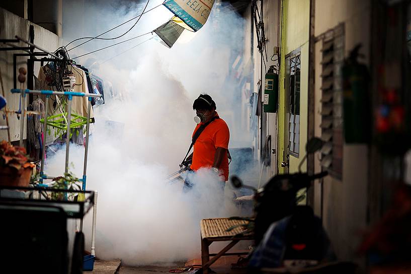 Бангкок, Таиланд. Рабочий распыляет средство против комаров в университете 