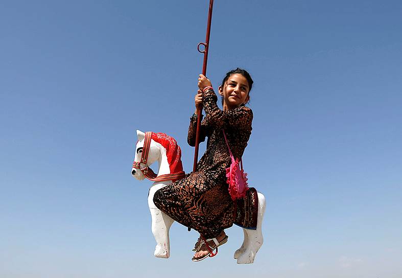 Кабул, Афганистан. Девочка катается на карусели на празднике Курбан-байрам