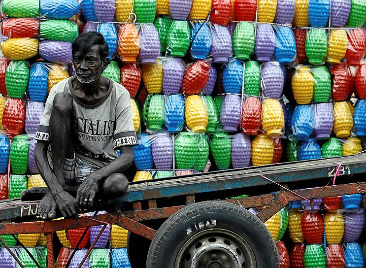 Коломбо, Шри-Ланка. Рабочий отдыхает после разгрузки пластиковых кувшинов в лавке на главном рынке страны