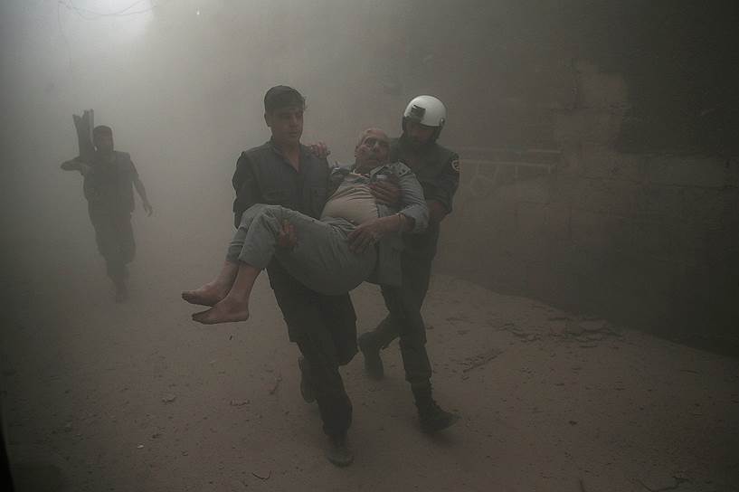 Дамаск, Сирия. Члены организации «Белые каски» спасают мужчину во время бомбардировки подконтрольной оппозиции части города