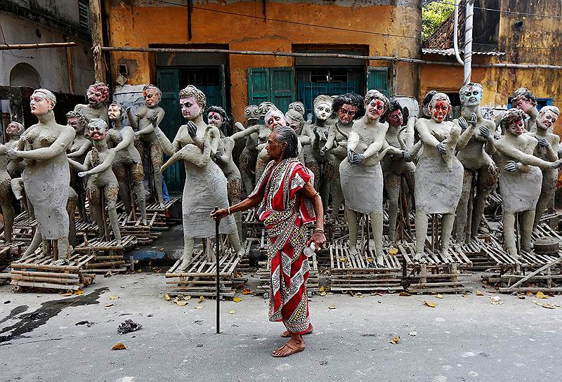Калькута, Индия. Женщина и глиняные заготовки мифических героев перед праздником Кали-пуджа