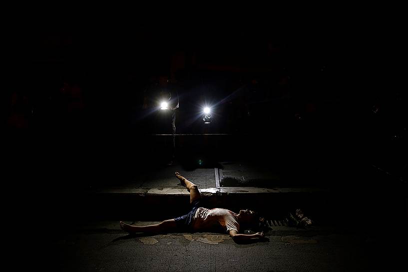 Манила, Филиппины. Тело убитого во время нарковойны человека подсвечивается видеокамерами местного телевидения