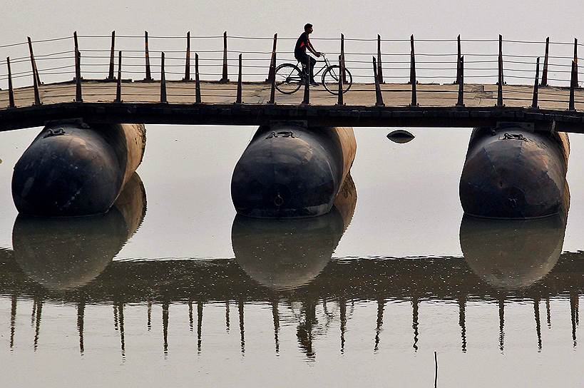 Аллахабад, Индия. Велосипедист проезжает по временному мосту через реку Ганг