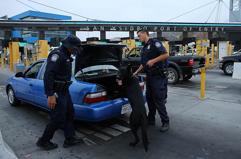 Сотрудники пограничных служб проверяют автомобиль мексиканца, который въезжает на территорию США