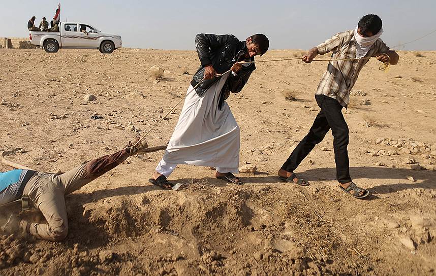 Карама, Ирак. Местные жители тащат террориста «Исламского государства», которого намерены закопать