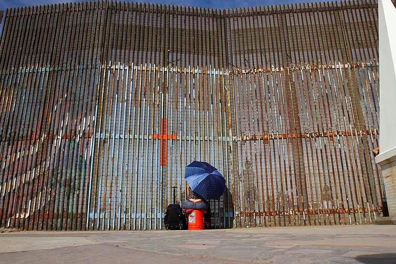 Тихуана, Мексика. Мексиканка общается со своими родственниками через забор на границе с США