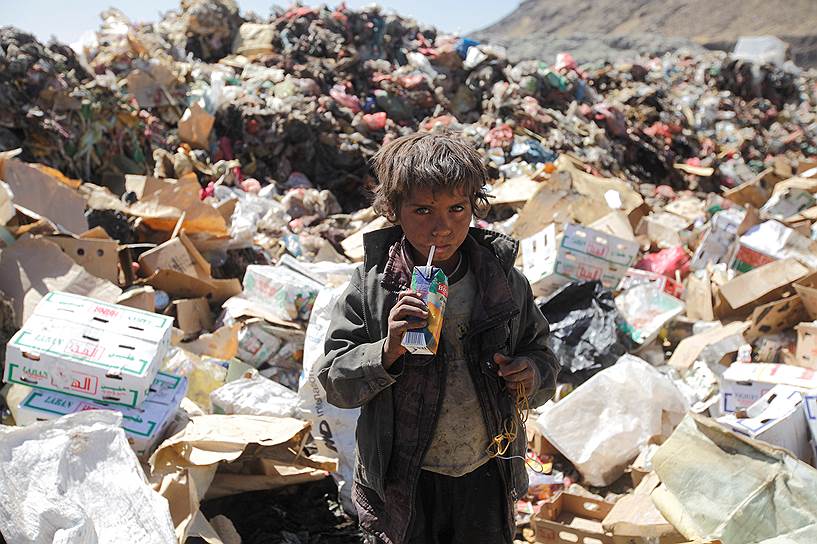 Сана, Йемен. Мальчик пьет сок из коробки, которую нашел на городской свалке