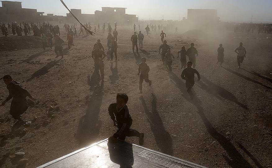 Мосул, Ирак. Местные жители бегут за грузовиком с гуманитарной помощью