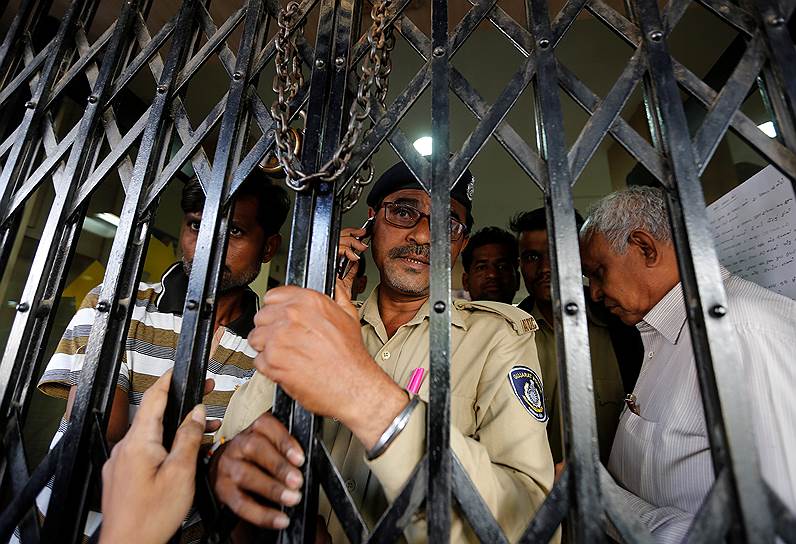 Ахмадабад, Индия. Полицейский закрывает двери банка перед людьми, которые пришли обменять старые купюры на новые