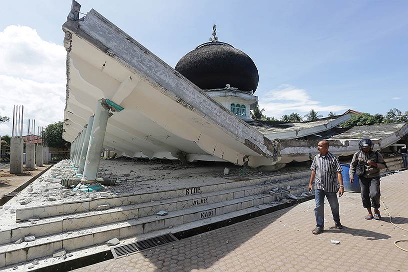 Ачех, Индонезия. Люди идут мимо разрушенной землетрясением мечети