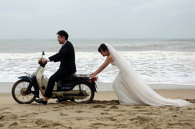 Хойан, Вьетнам. Невеста толкает скутер, на котором едет ее жених, во время свадебной фотосессии