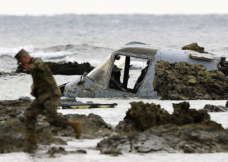 Наго, Япония. Солдат армии США рядом с обломками военного конвертоплана MV-22, который потерпел крушение в море