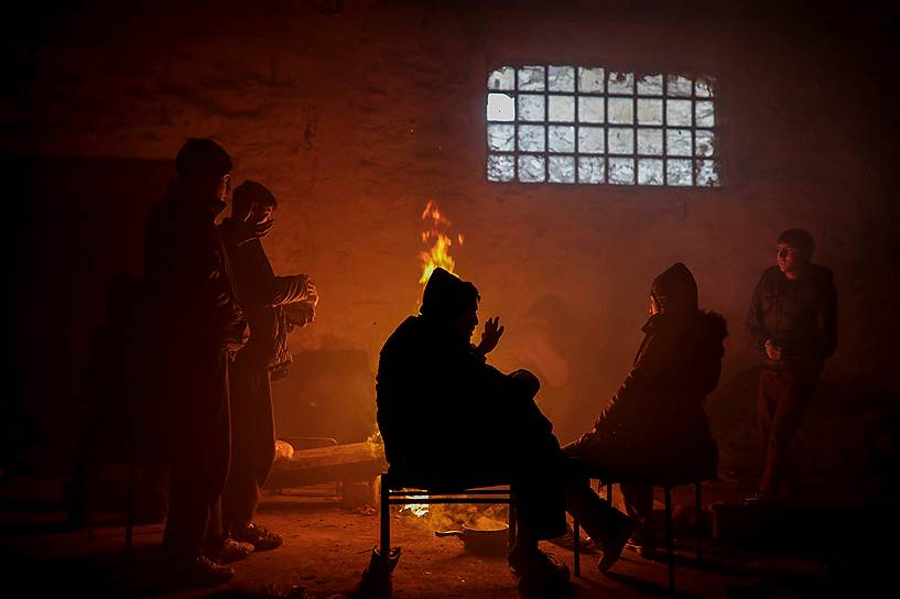 Белград, Сербия. Мигранты греются у огня в здании бывшего таможенного склада, где они организовали стихийный лагерь